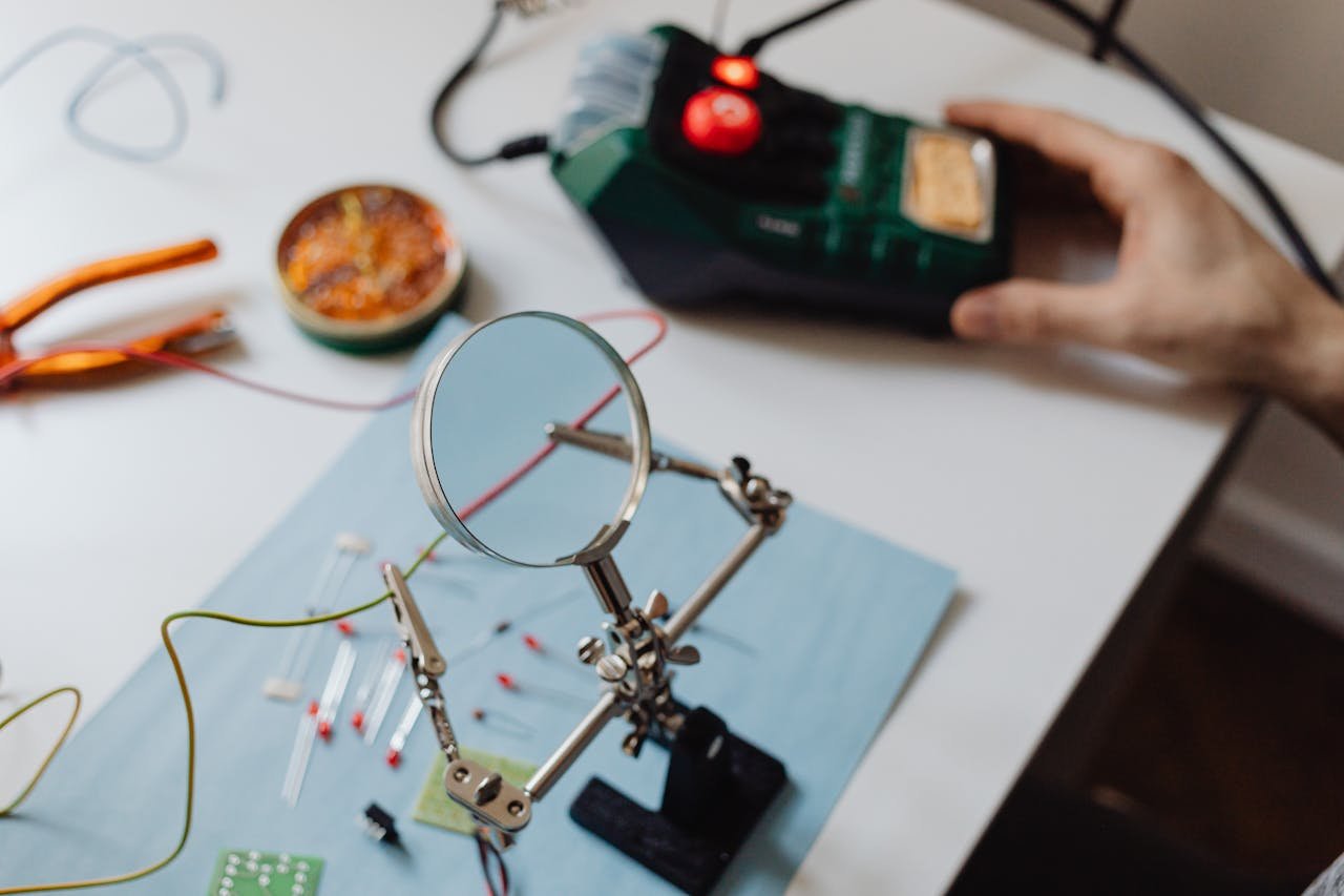 Close-up of a technician's workspace with magnifying glass and soldering tools.